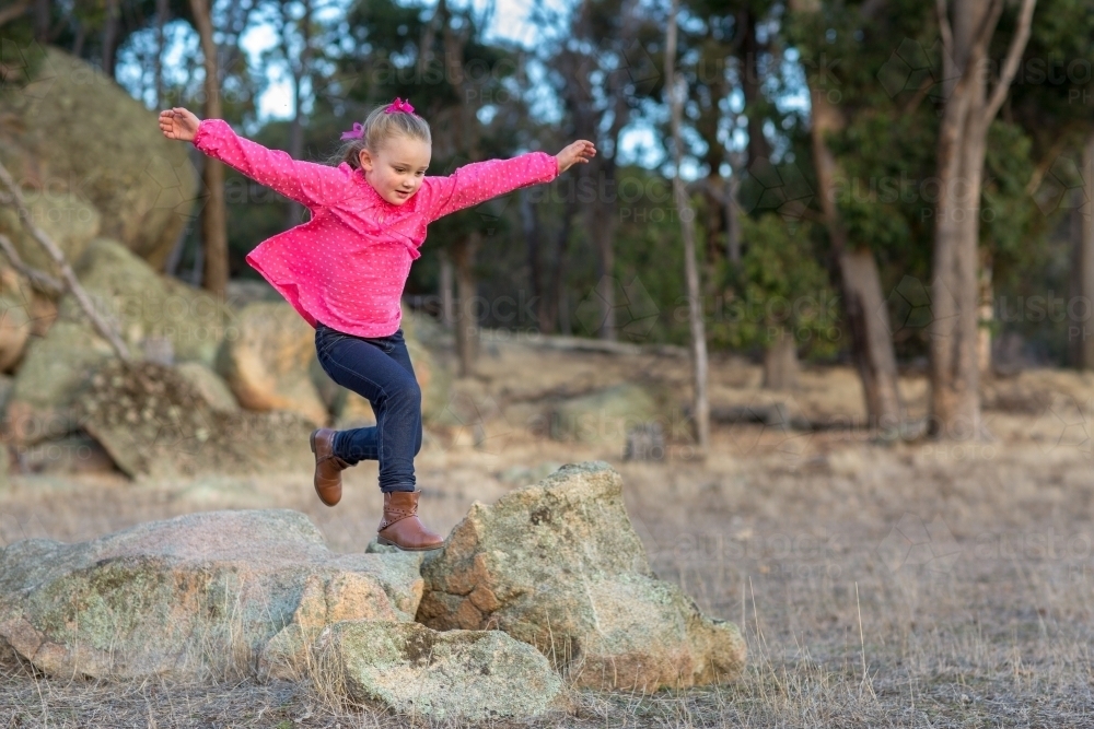 Image of Kid jumping on rocks - Austockphoto