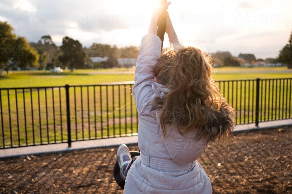 Kid playing at the park outdoors swinging - Australian Stock Image