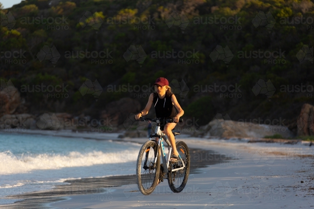 Kid riding bike on beach - Australian Stock Image