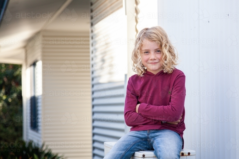 Kid sitting outside with crossed arms - Australian Stock Image