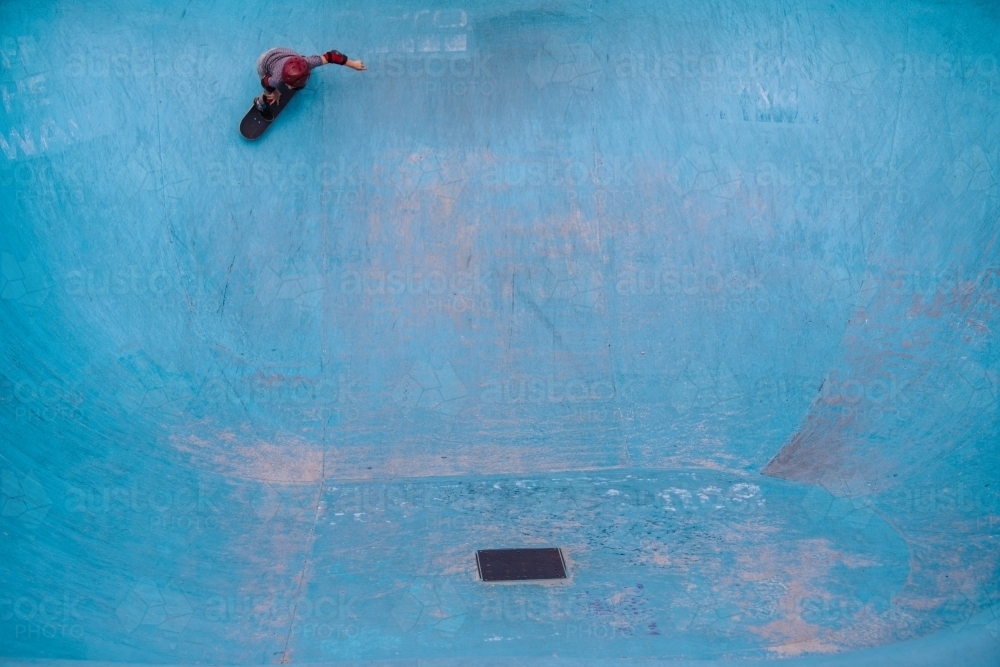 Kid skateboarding in a blue empty pool - Australian Stock Image