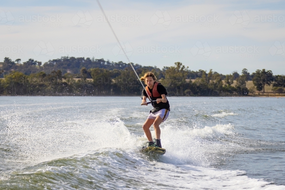 kid wakeboarding on fresh water lake - Australian Stock Image