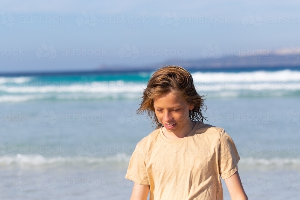 Kid walking with wind in hair at beach - Australian Stock Image