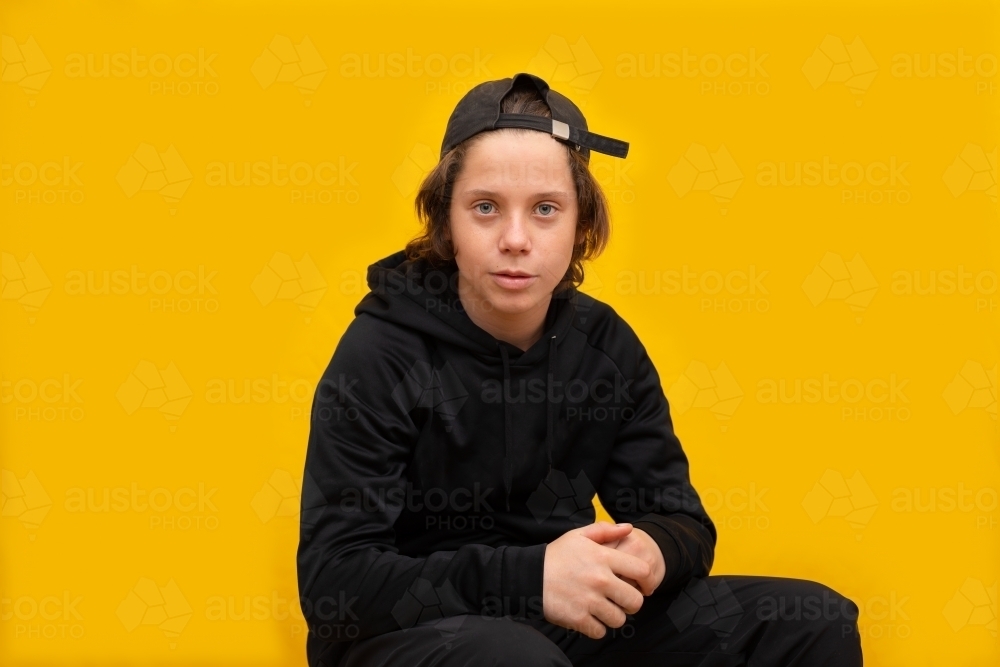 kid wearing black against a bright yellow background - Australian Stock Image