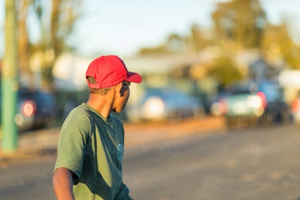 kid wearing red cap looking away over his shoulder - Australian Stock Image