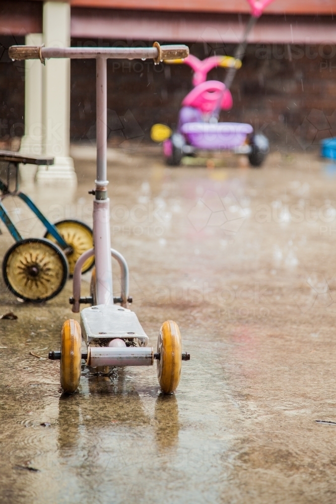 Kids bikes and toys left outside in the rain - Australian Stock Image