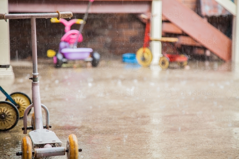 Kids bikes and toys left outside in the rain - Australian Stock Image