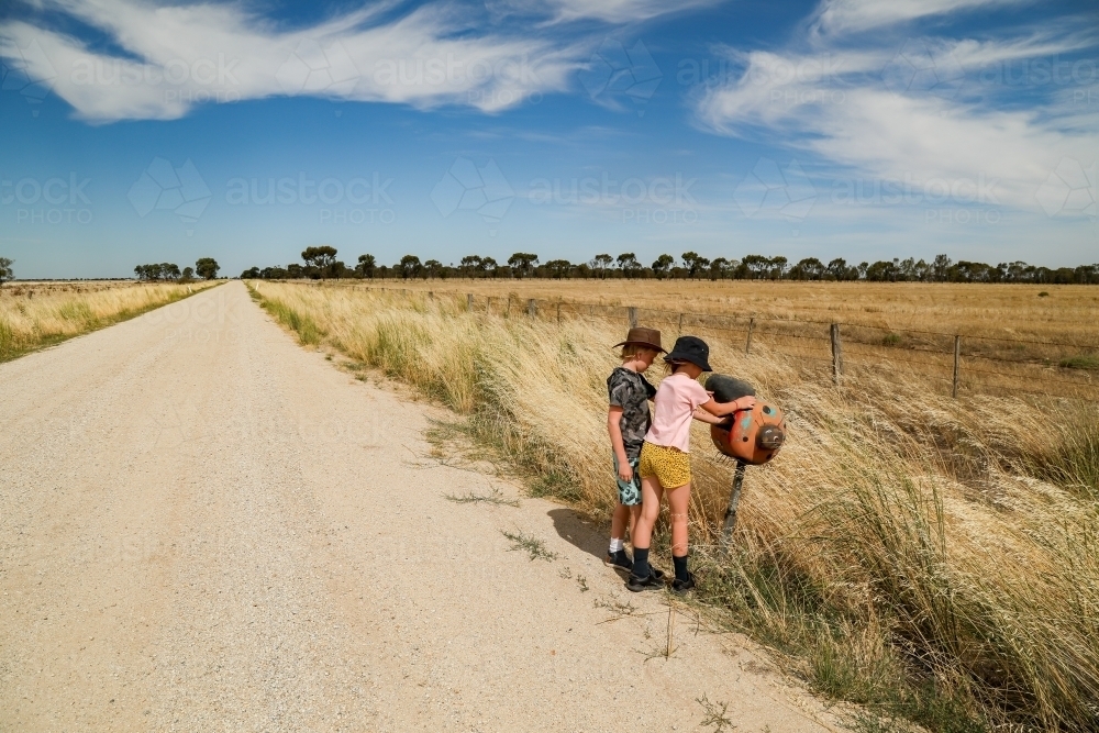Kids checking ladybird mailbox on rural country road - Australian Stock Image