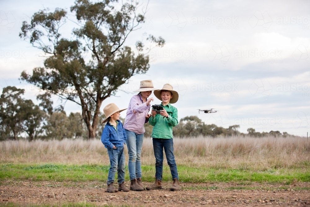 Kids flying a drone in a farm paddock - Australian Stock Image