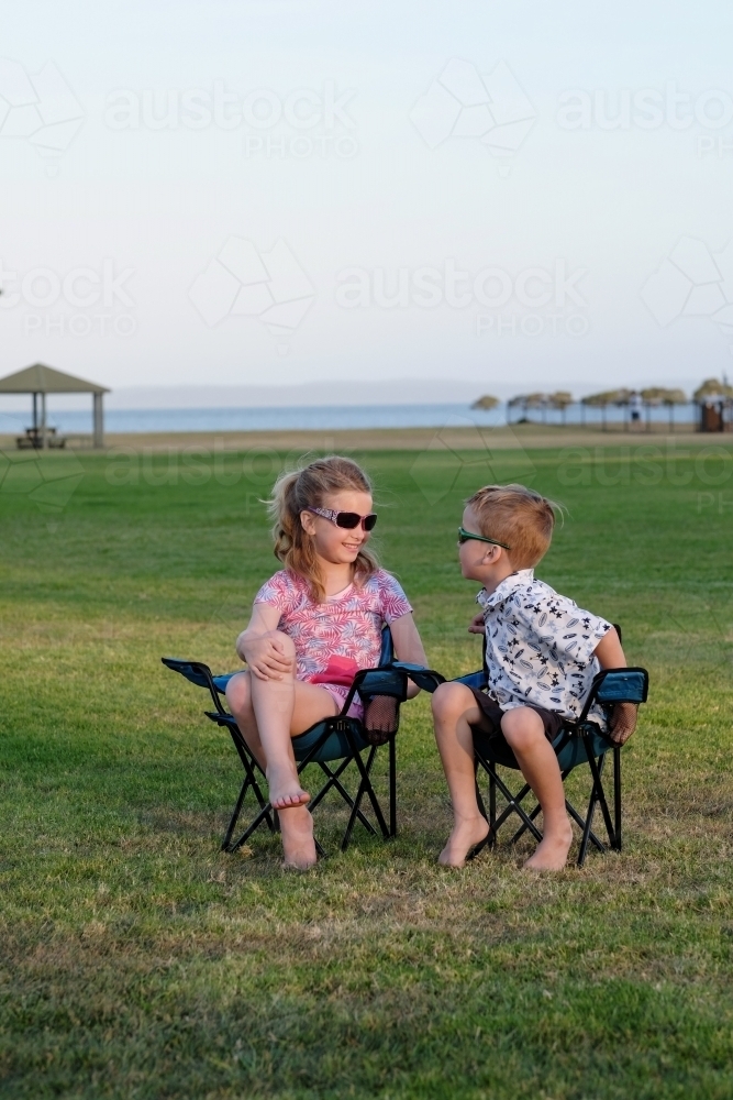 Kids having fun in camping chairs on the grass - Australian Stock Image