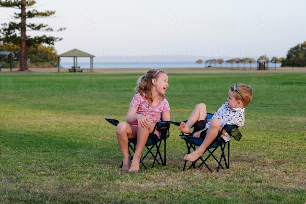Kids having fun in camping chairs on the grass - Australian Stock Image