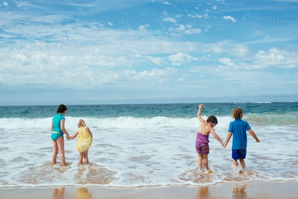 Kids holding hands in surf - Australian Stock Image