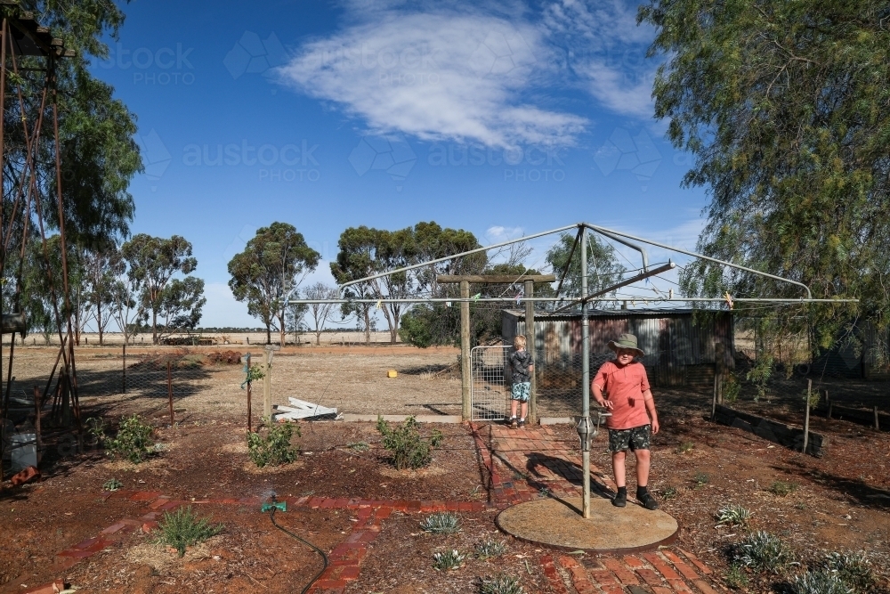 Kids in rural dry backyard in summertime with hills hoist washing line - Australian Stock Image