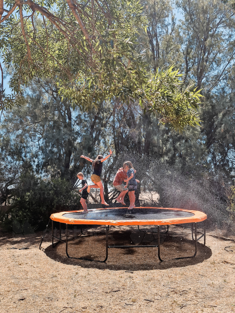 Kids jumping on trampoline in Aussie backyard in the summer - Australian Stock Image