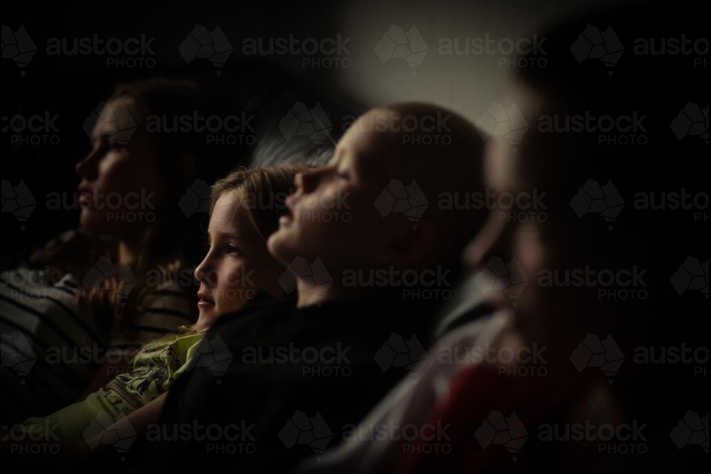 Kids lined up on the Sofa - staring into the TV - Australian Stock Image