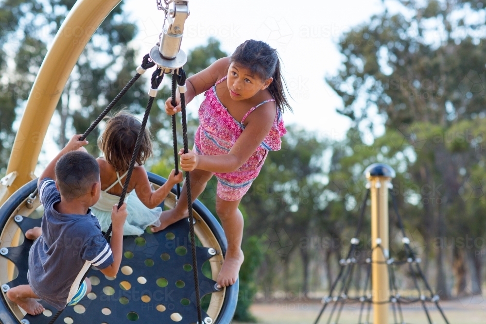 Kids on a swing in a playground - Australian Stock Image