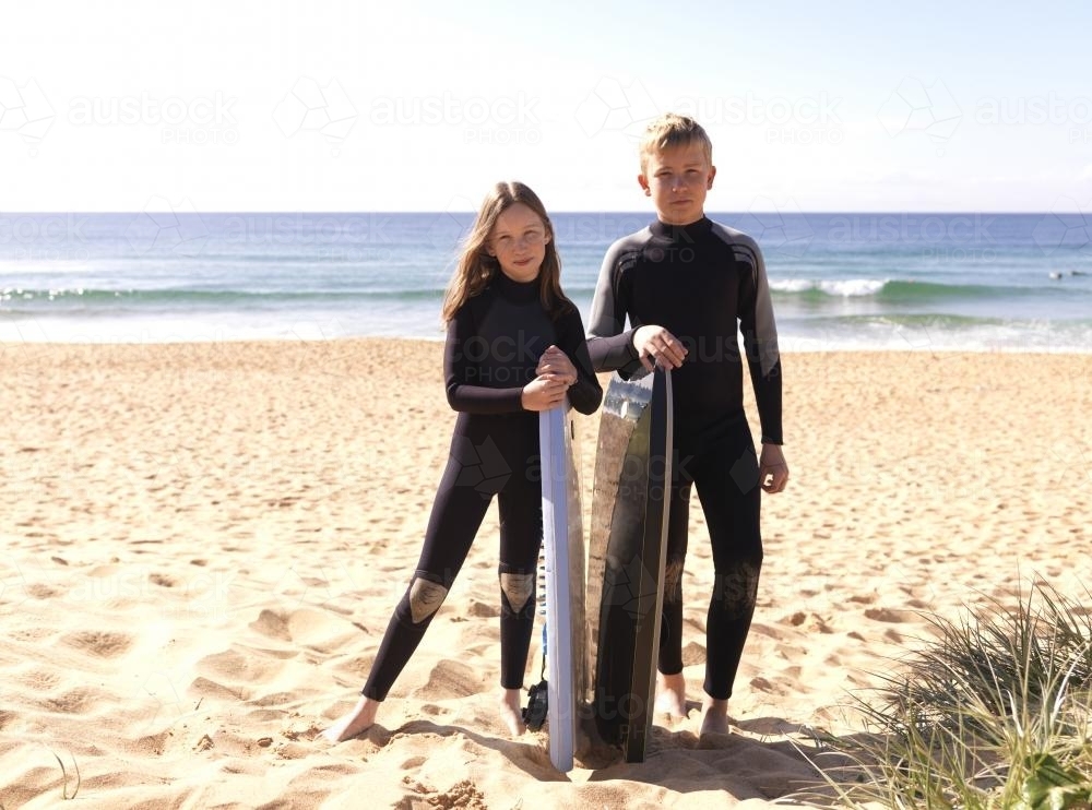 Kids on beach in wetsuits preparing to go body boarding - Australian Stock Image