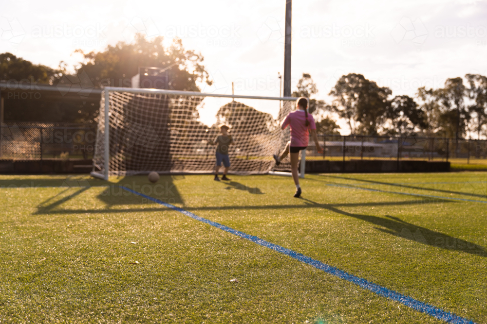kids playing soccer with a goalie and striker - Australian Stock Image