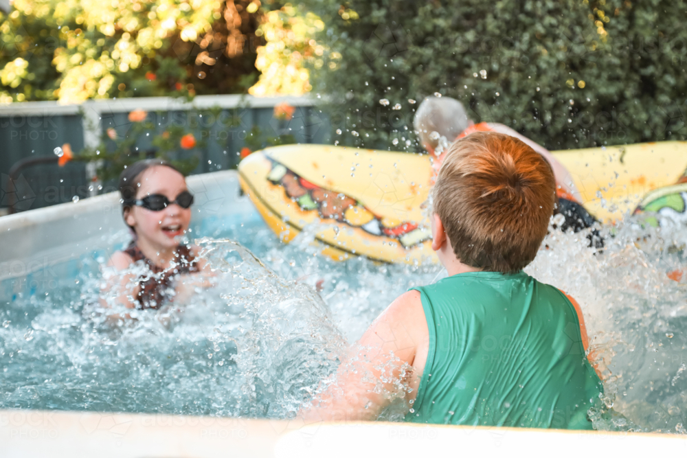 Kids playing with inflatable taco in backyard swimming pool - Australian Stock Image