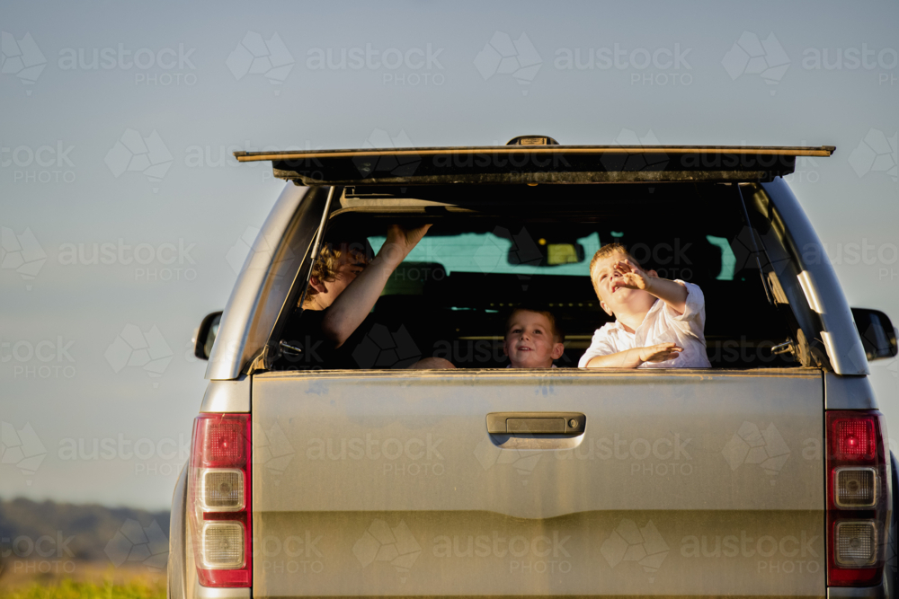 Kids sitting in the back of ute on farm - Australian Stock Image