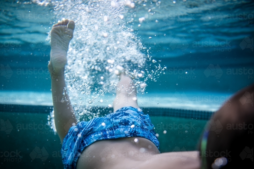 Kids swim and kick under water in their backyard pool - Australian Stock Image