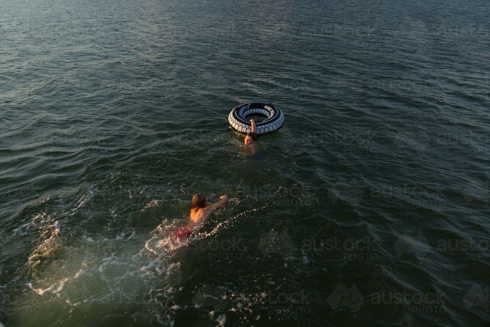 Kids swimming with an inflatable tube - Australian Stock Image