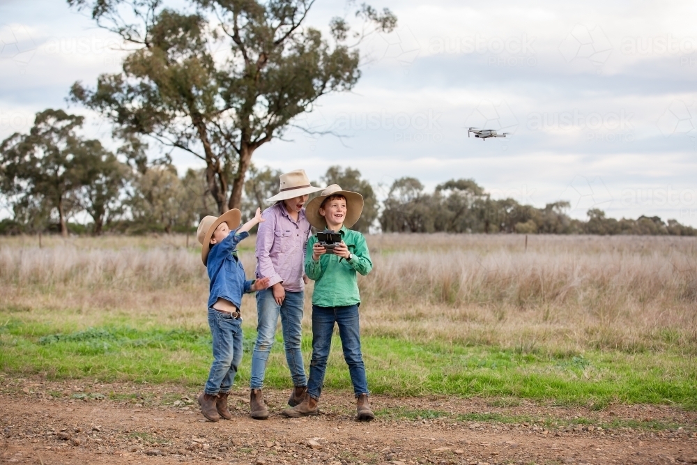 Kids using a drone in a farm paddock - Australian Stock Image