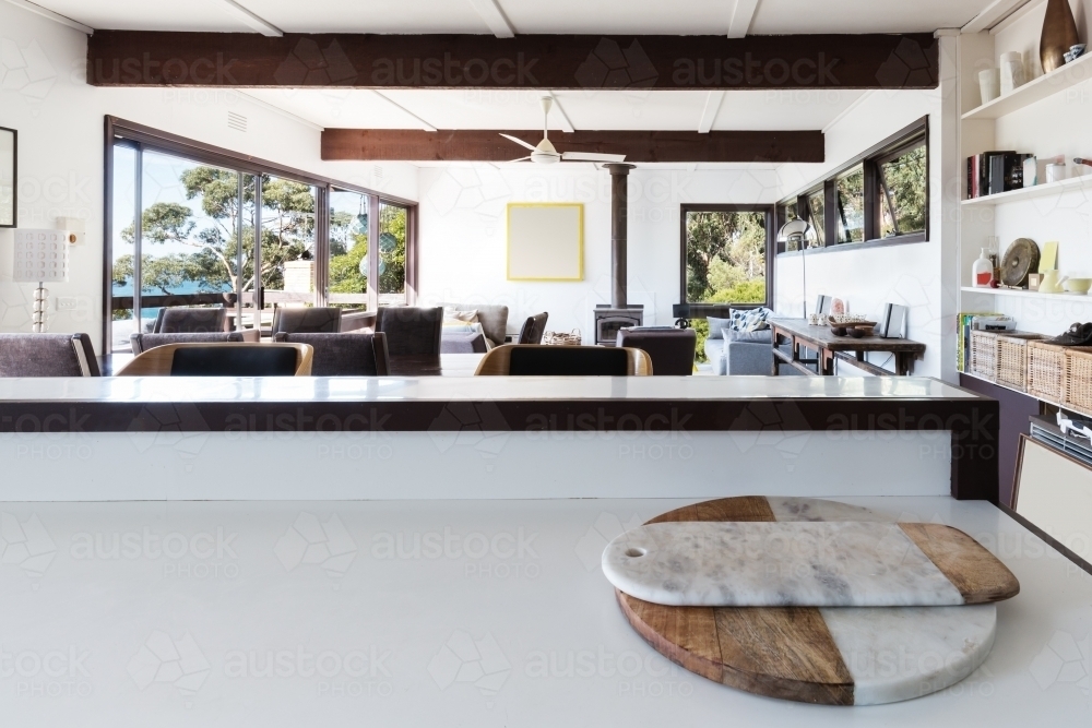Kitchen bench looking to open plan living room in retro beach home - Australian Stock Image