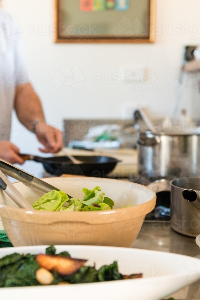 Kitchen scene with bowls of food and man cooking in the background - Australian Stock Image