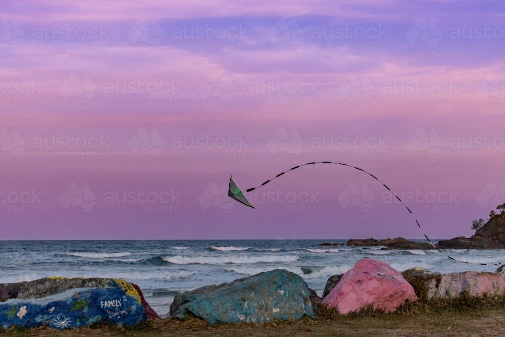 Kite flying over the Port Macquarie breakwall at sunset in pink sky - Australian Stock Image