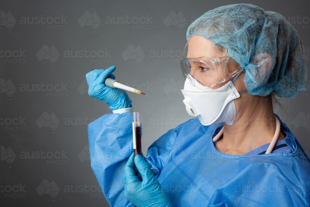 Laboratory pathologist healthcare worker holding a pipette blood sample for analysis - Australian Stock Image