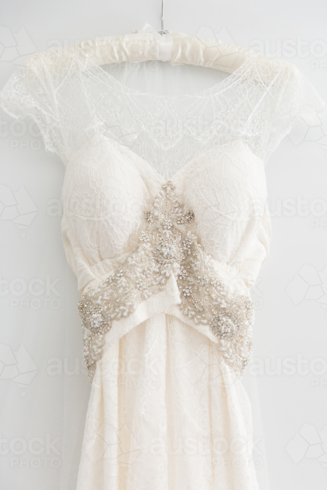 lace and bejewelled wedding dress on a hanger - Australian Stock Image