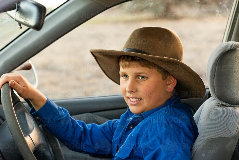 lad wearing hat at the wheel of a car - Australian Stock Image