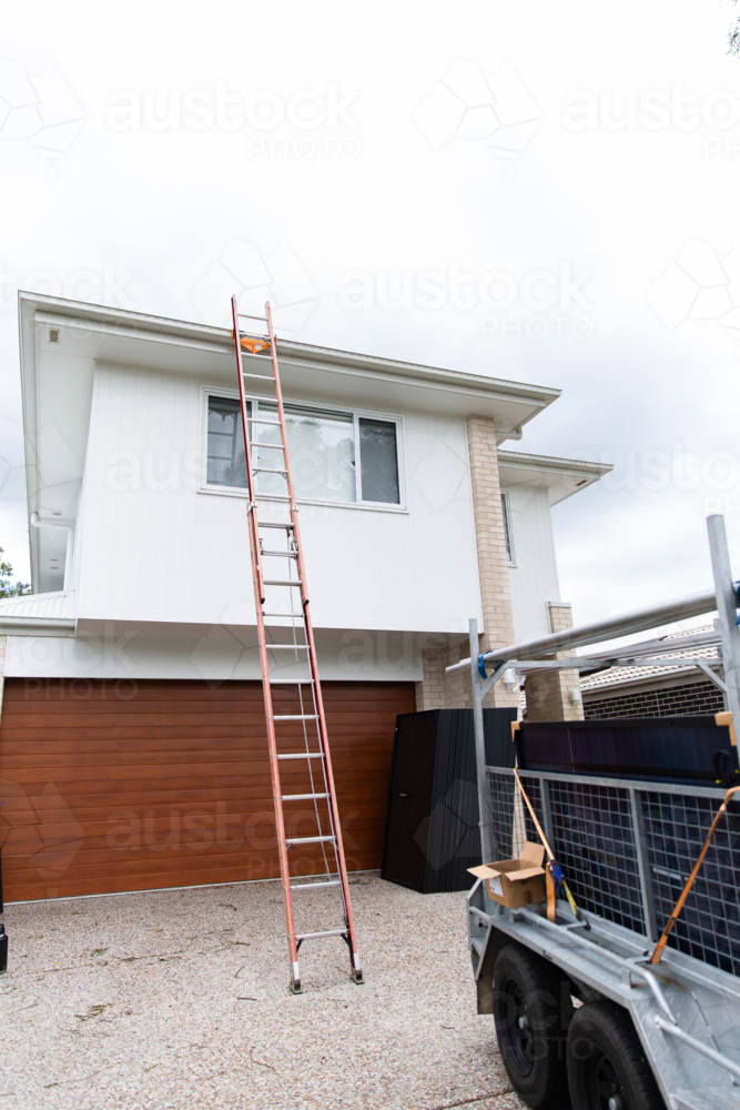 ladder up to a roof on a 2 storey house to install solar panels - Australian Stock Image
