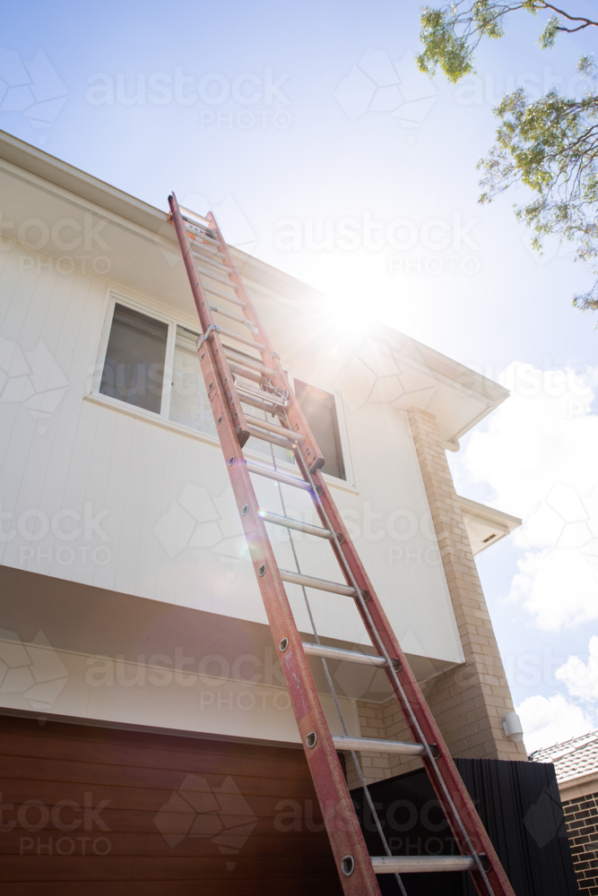ladder up to the roof of a two storey house to install solar panels - Australian Stock Image