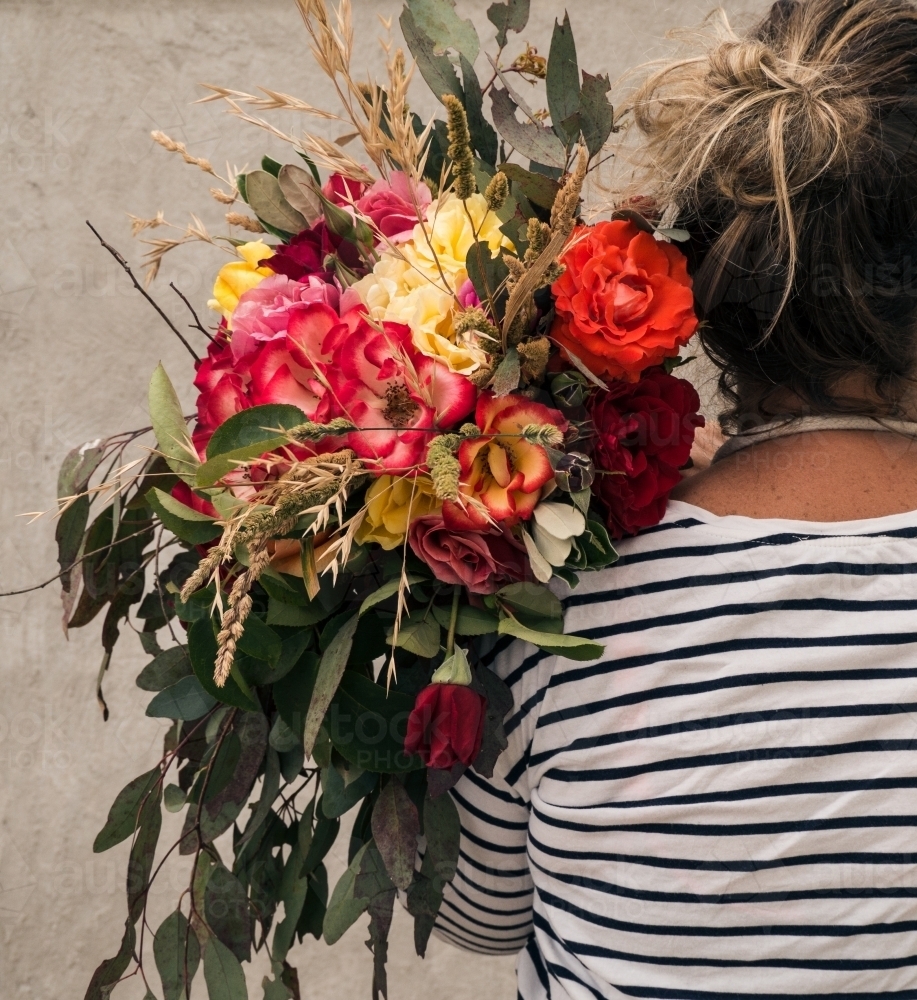 lady florist holding big bunch of flowers over her shoulder - Australian Stock Image