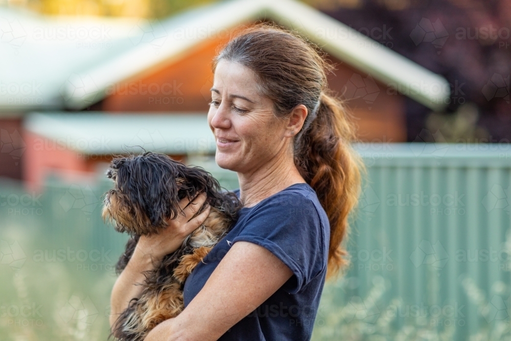 lady holding a little dog outdoors - Australian Stock Image