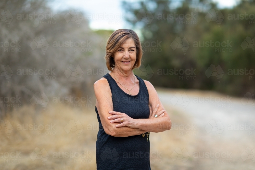 lady in black with crossed arms standing on the side of pathway - Australian Stock Image