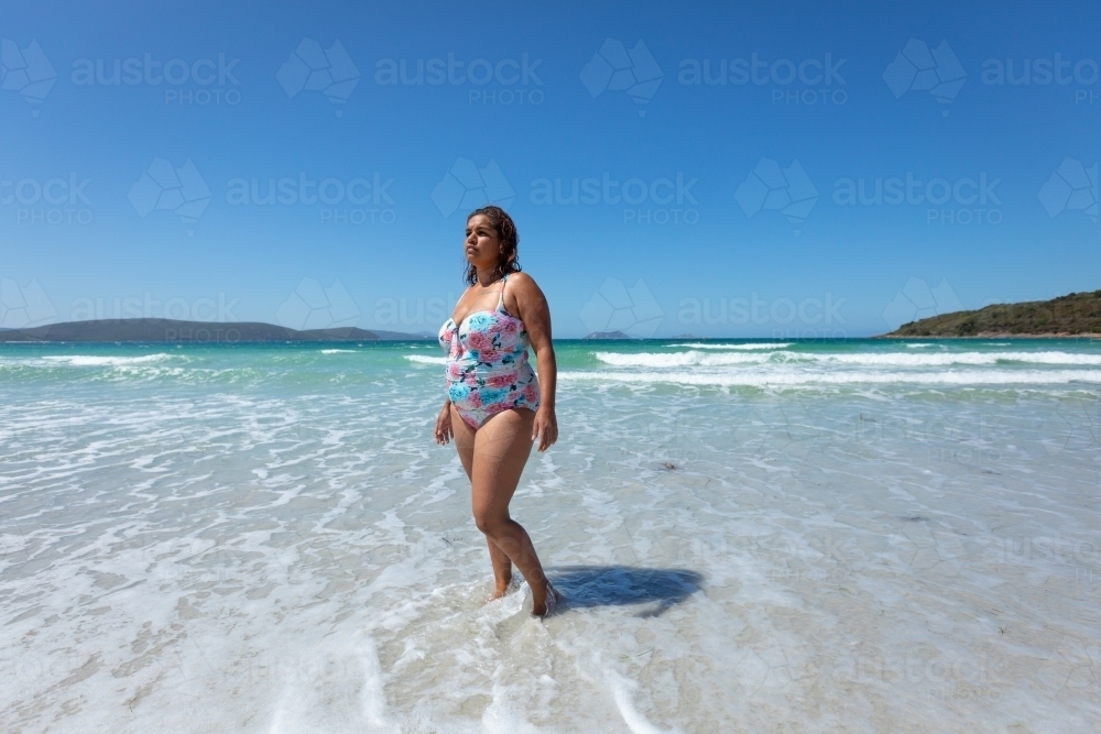 lady in swimming costume standing in shallows on the beach - Australian Stock Image