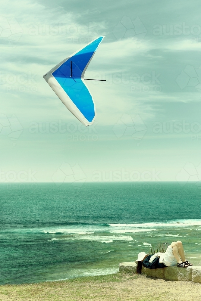 Lady resting with hang glider above on a beautiful day - Australian Stock Image