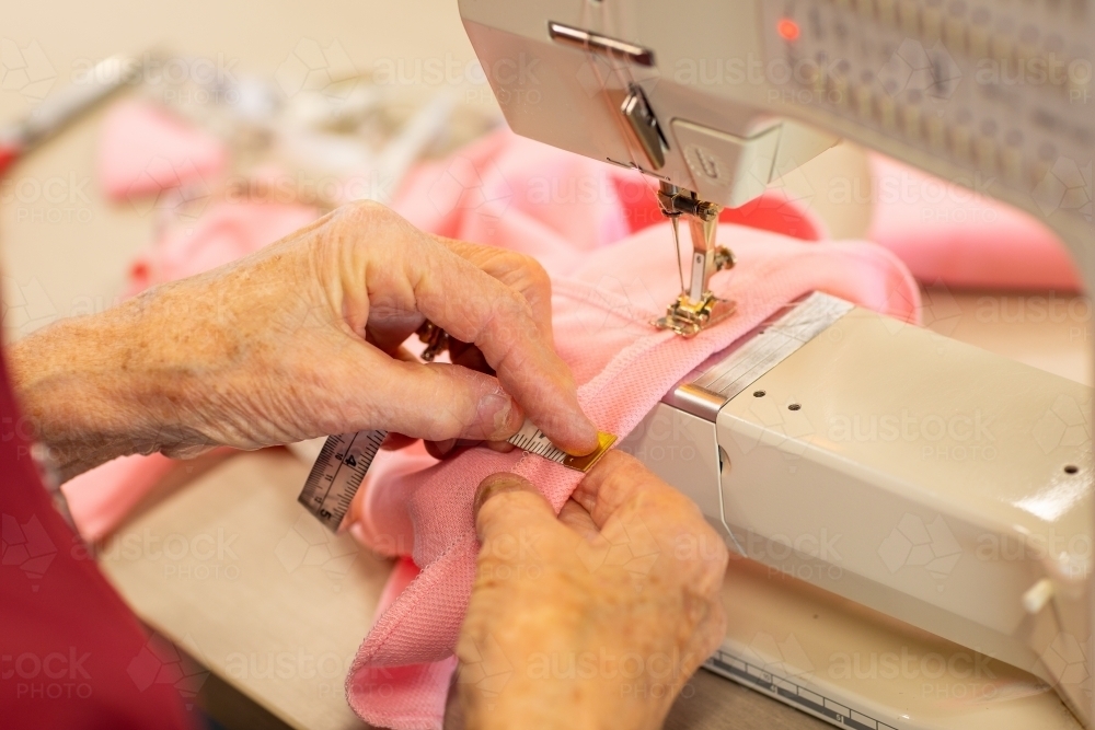 lady's hands measuring hem on garment she is sewing - Australian Stock Image