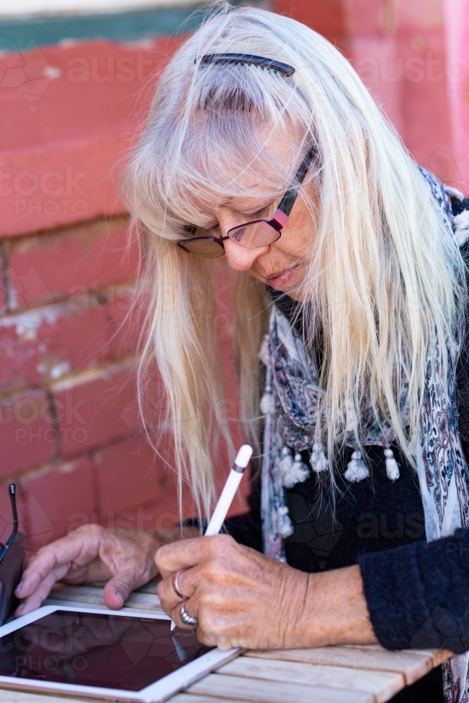 Lady using digital pencil to write on tablet - Australian Stock Image