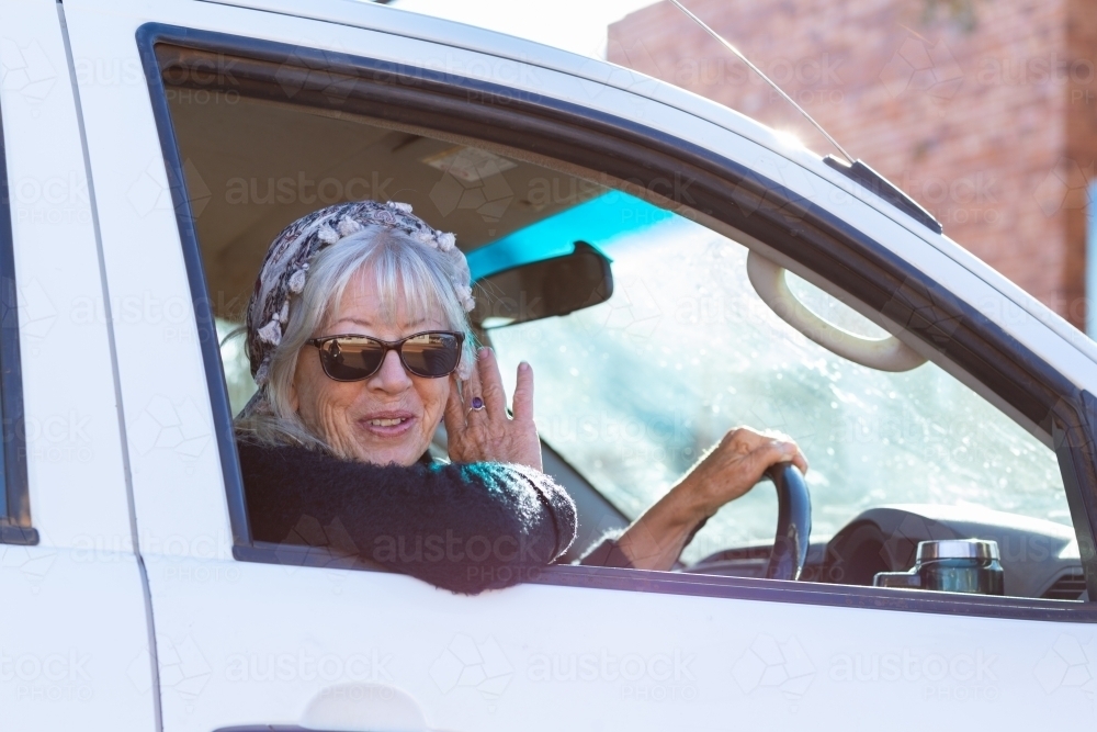 lady wearing sunglasses looking out of car window while driving - Australian Stock Image