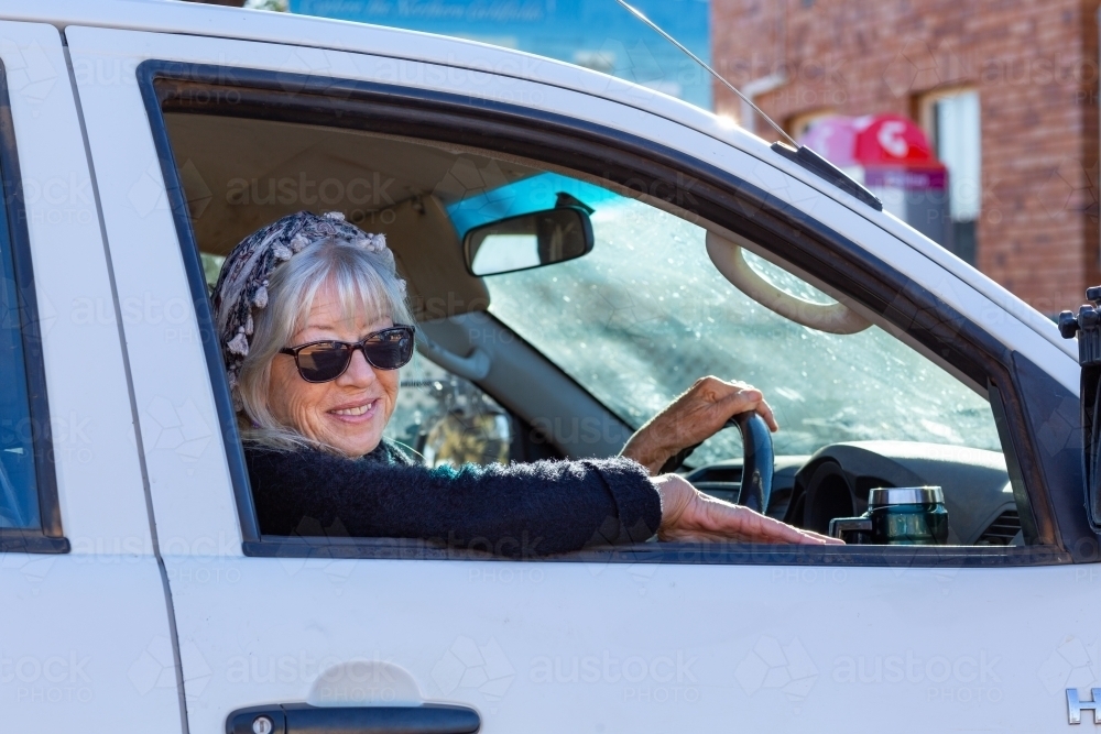 lady wearing sunglasses looking out of car window while driving - Australian Stock Image