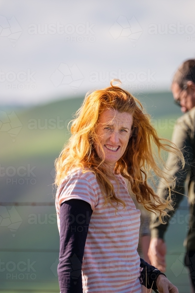 Lady with bright red hair blowing in the wind. - Australian Stock Image