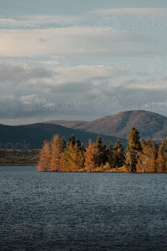 Lake Jindabyne at sunset with autumn coloured trees and mountains - Australian Stock Image
