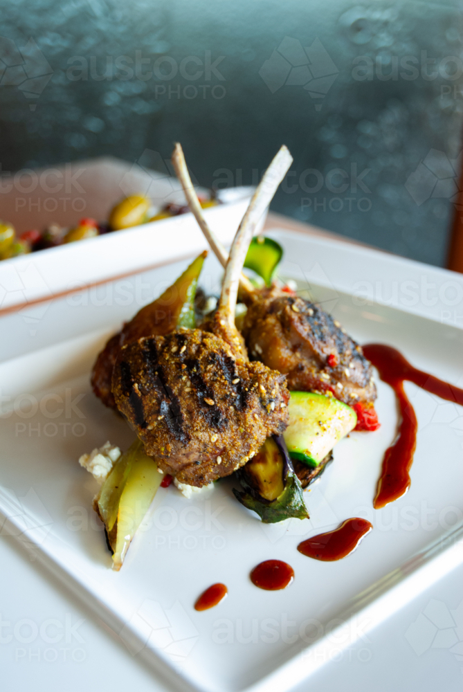 Lamb cutlets on a plate with vegetables and sauce - Australian Stock Image