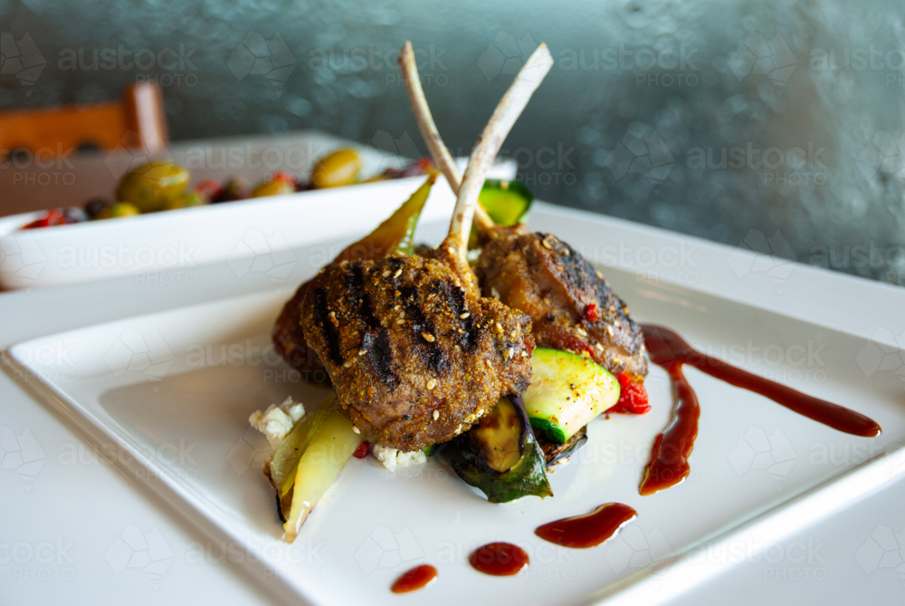 Lamb cutlets with vegetables and sauce on a plate - Australian Stock Image
