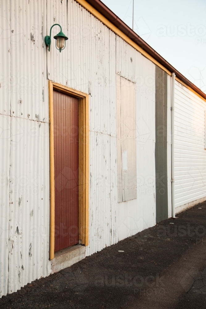 Lamp above door of corrugated building beside footpath - Australian Stock Image