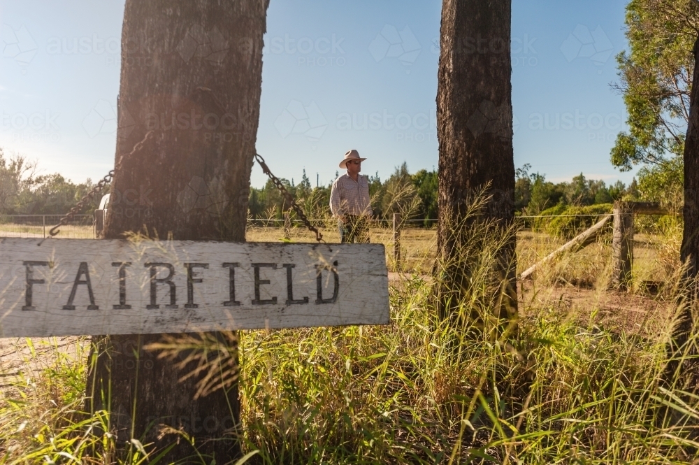 landowner standing in the driveway of his rural property, with sign in the foreground - Australian Stock Image